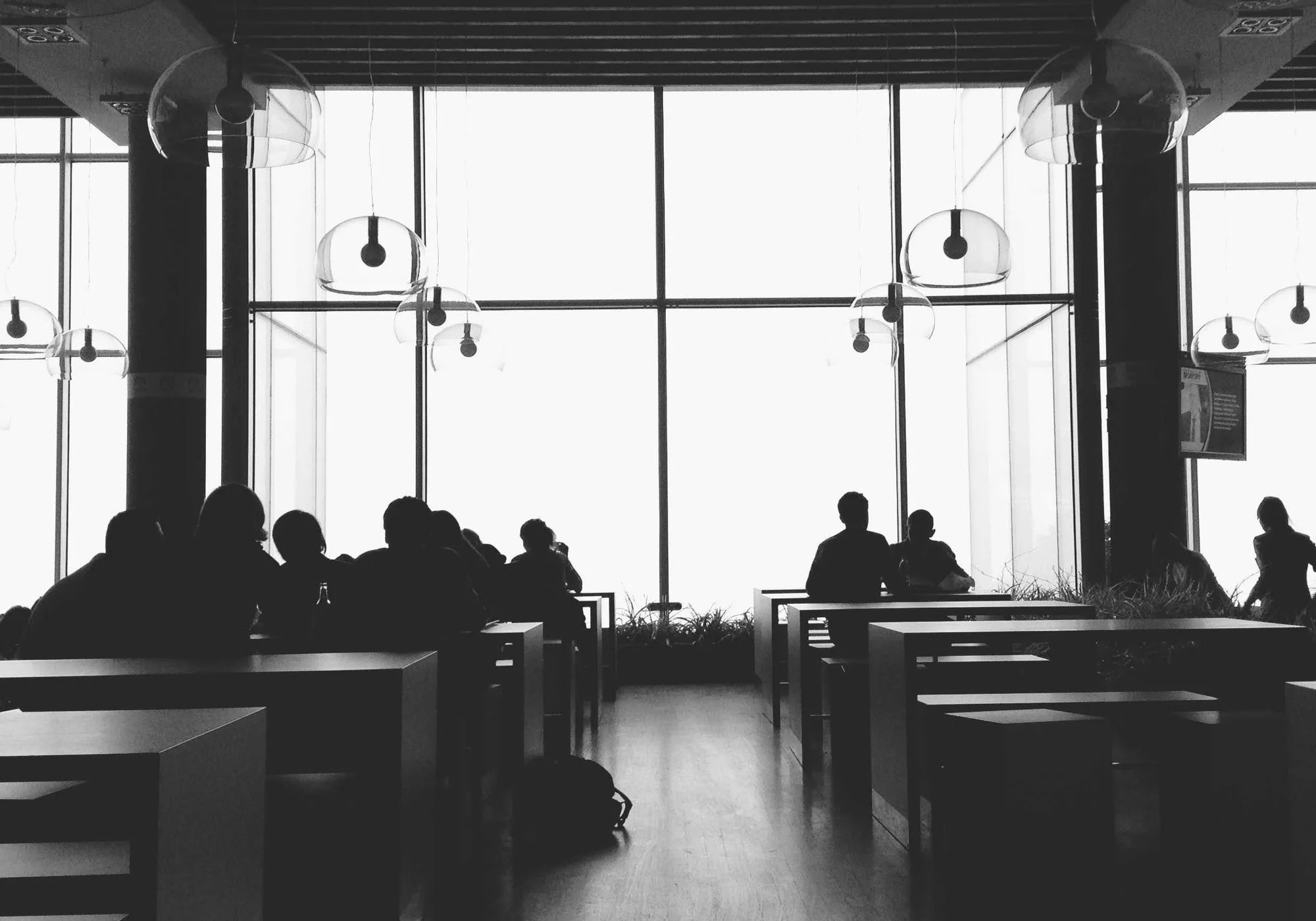 Silhouetten von Menschen vor einer großen Glasfront
